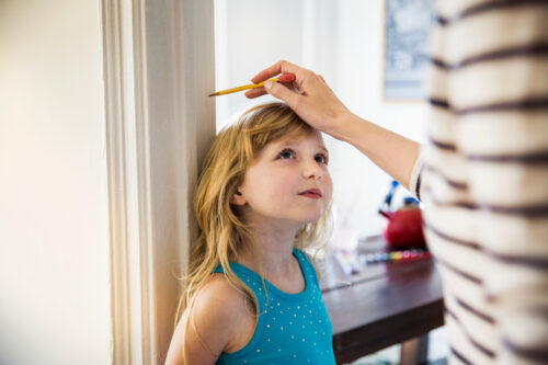 Midsection of woman measuring daughter's height